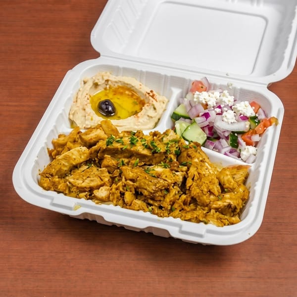 Chicken shawarma platter with hummus, salad, and chicken in a white takeout container.