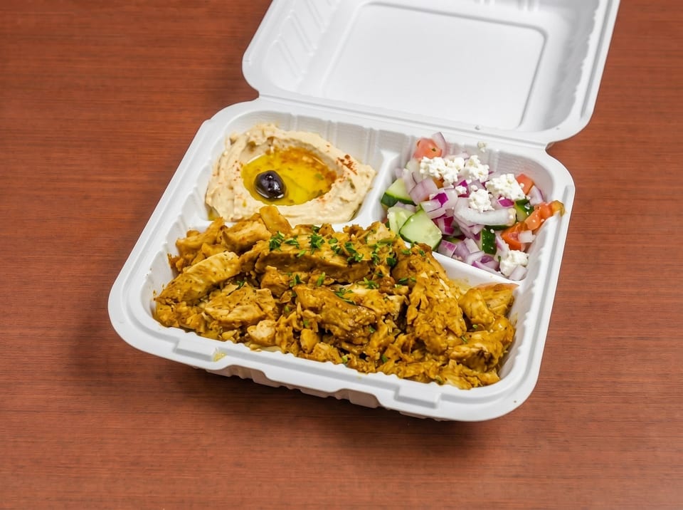 Chicken shawarma platter with hummus, salad, and chicken in a white takeout container.
